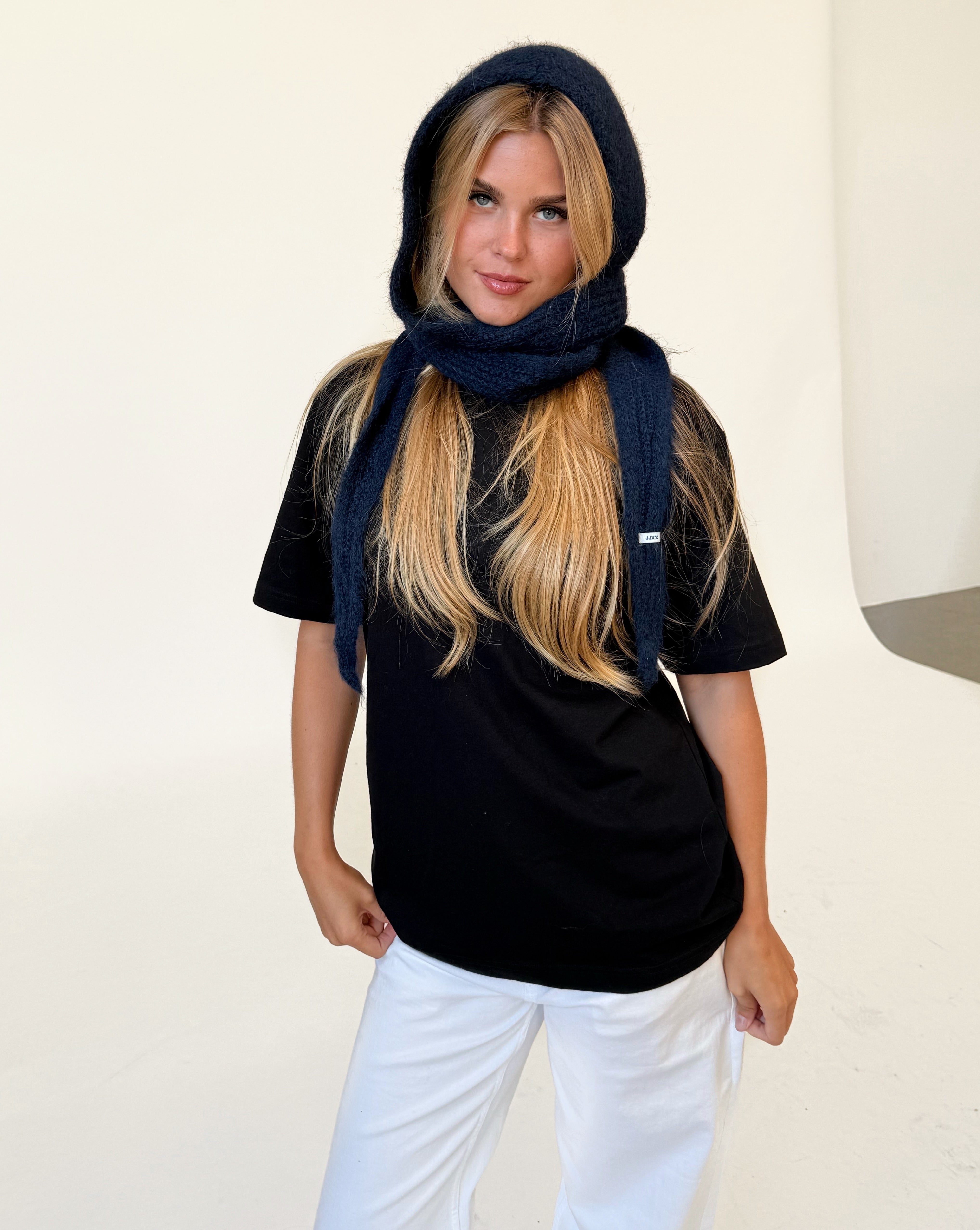 Modelfoto af pige iført navy KATHERINE balaclava, mørkblå t-shirt og hvide NANNA jeans. Alt er fra BySofieSønderby.