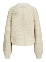 Trøje i beige, grov strik ligger fladt mod hvid baggrund. Den har lange ærmer og en rund halsudskæring, der skaber et hyggeligt og stilfuldt look.
