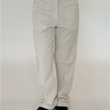 Bukser, iført af en person, er lyse og vide, parret med sorte sko. Baggrunden er enkel og hvid, hvilket fremhæver det minimalistiske look.