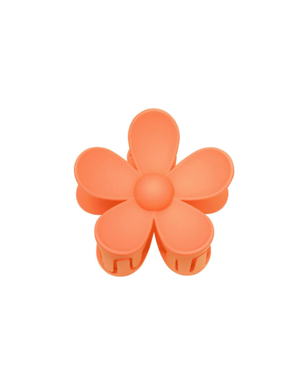 Orange blomstformet hårklemme med seks kronblade, ligger på en hvid baggrund.