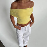 Modelfoto af pige som bærer en Leia top i gul, samt et par hvide Nanna jeans. Alt fra By Sofie Sønderby