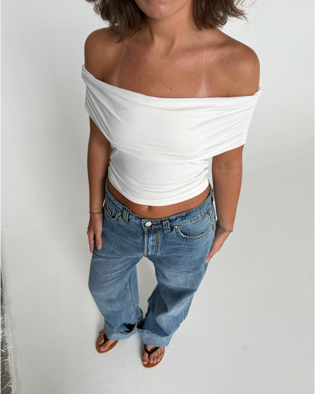 Modelfoto af pige som bærer en Leia top i hvid, samt et par hvide Nanna jeans. Alt fra By Sofie Sønderby