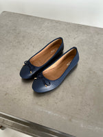 To mørkeblå ballerina-sko med sløjfer er placeret side om side på en grå overflade. Indersålen har mærketext, der siger "ALDO" og "8 UK 41 EUR".