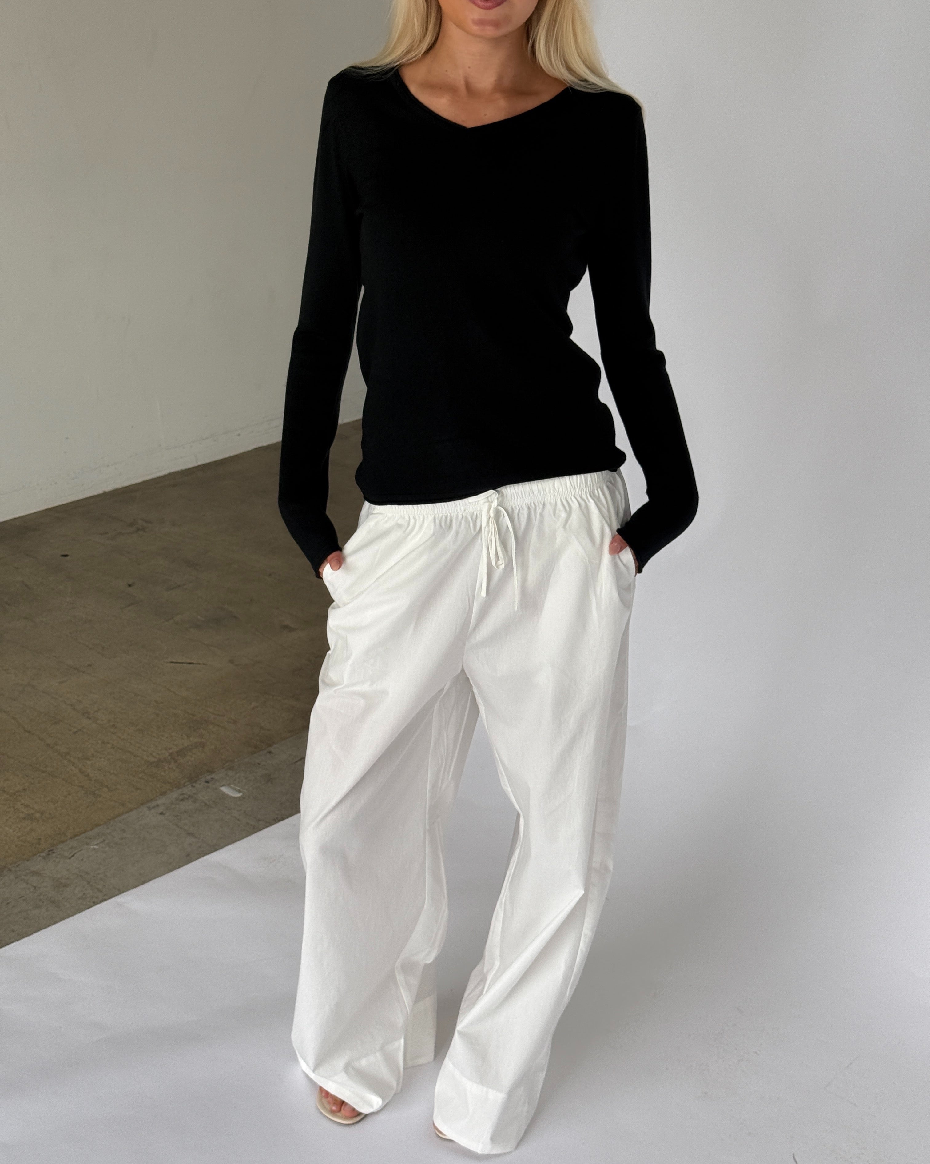 Modelbillede af LILLIE langærmet v-hals, sort og DANIA wide leg bukser, hvid. Begge fra BySofieSønderby
