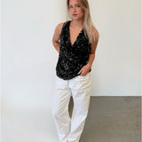Modelfoto af pige i sort LINA top med pailetter, samt hvide NANNA jeans. Alt er fra BySofieSønderby.
