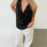 Modelfoto af pige i sort LINA top med pailetter, samt hvide NANNA jeans. Alt er fra BySofieSønderby.