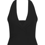 Sort halterneck-top med dyb V-udskæring, båret uden synlige detaljer eller mønstre, mod en ensfarvet baggrund, fremstillet af glat stof med let elastisk udseende.