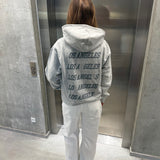 Stemningsbillede af pige der bærer en grå hoodie med gråt LOS ANGELES tryk og hvide NANNA jeans.  Fra BySofieSønderby