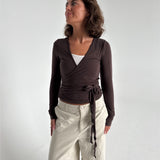 Modelfoto af pige i brun Luna wrapbluse og beige bukser. Fra BySofieSønderby