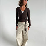 Modelfoto af pige i brun Luna wrapbluse og beige bukser. Fra BySofieSønderby