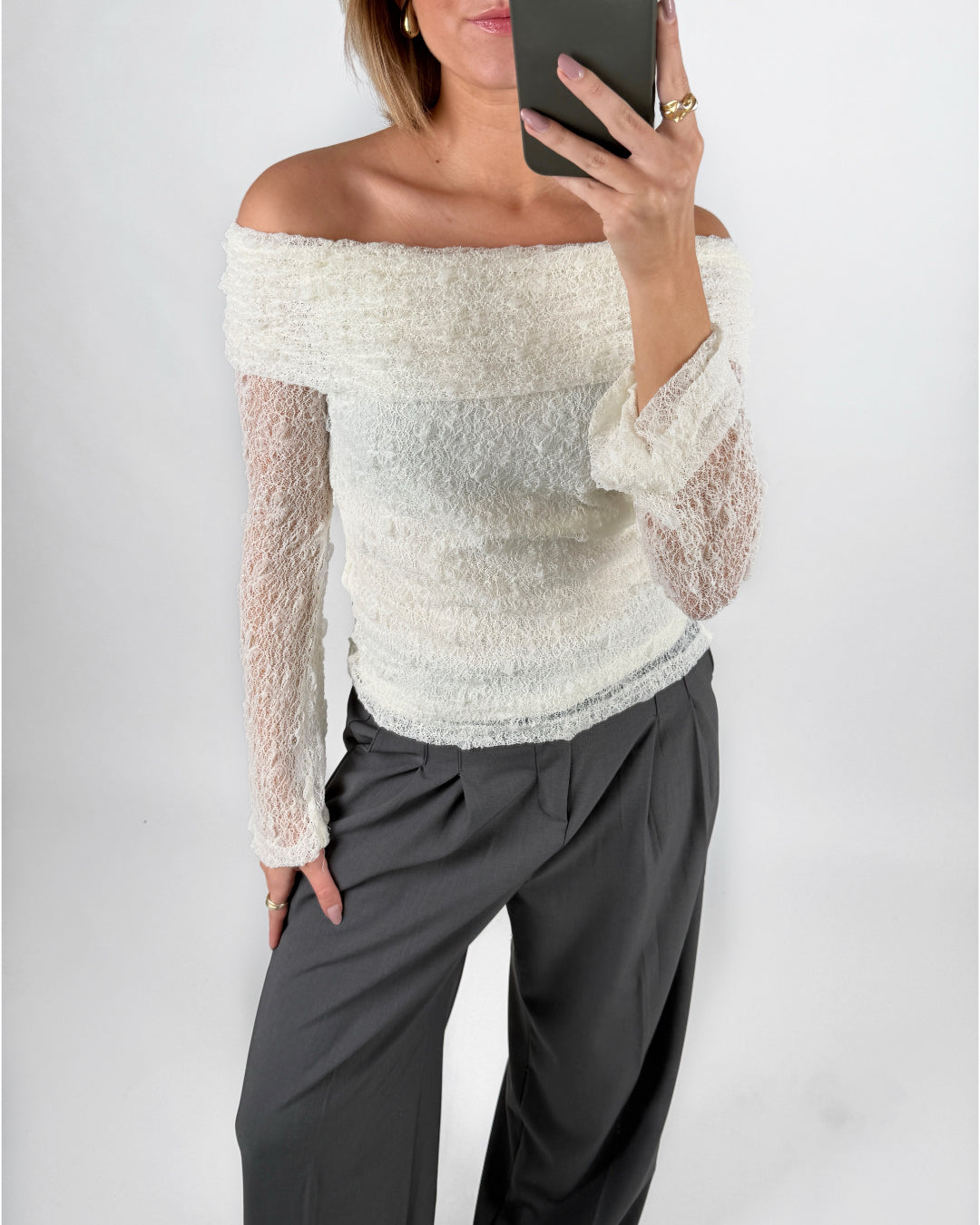 Modelfoto af pige i cremefarvet MAISY off-shoulder blondebluse og grå LISA bukser. Alt er fra BySofieSønderby.