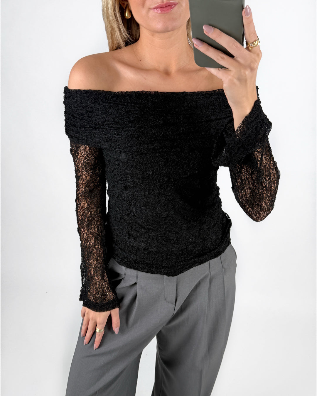 Modelfoto af pige i sort MAISY off-shoulder blondebluse og grå LISA bukser. Alt er fra BySofieSønderby.