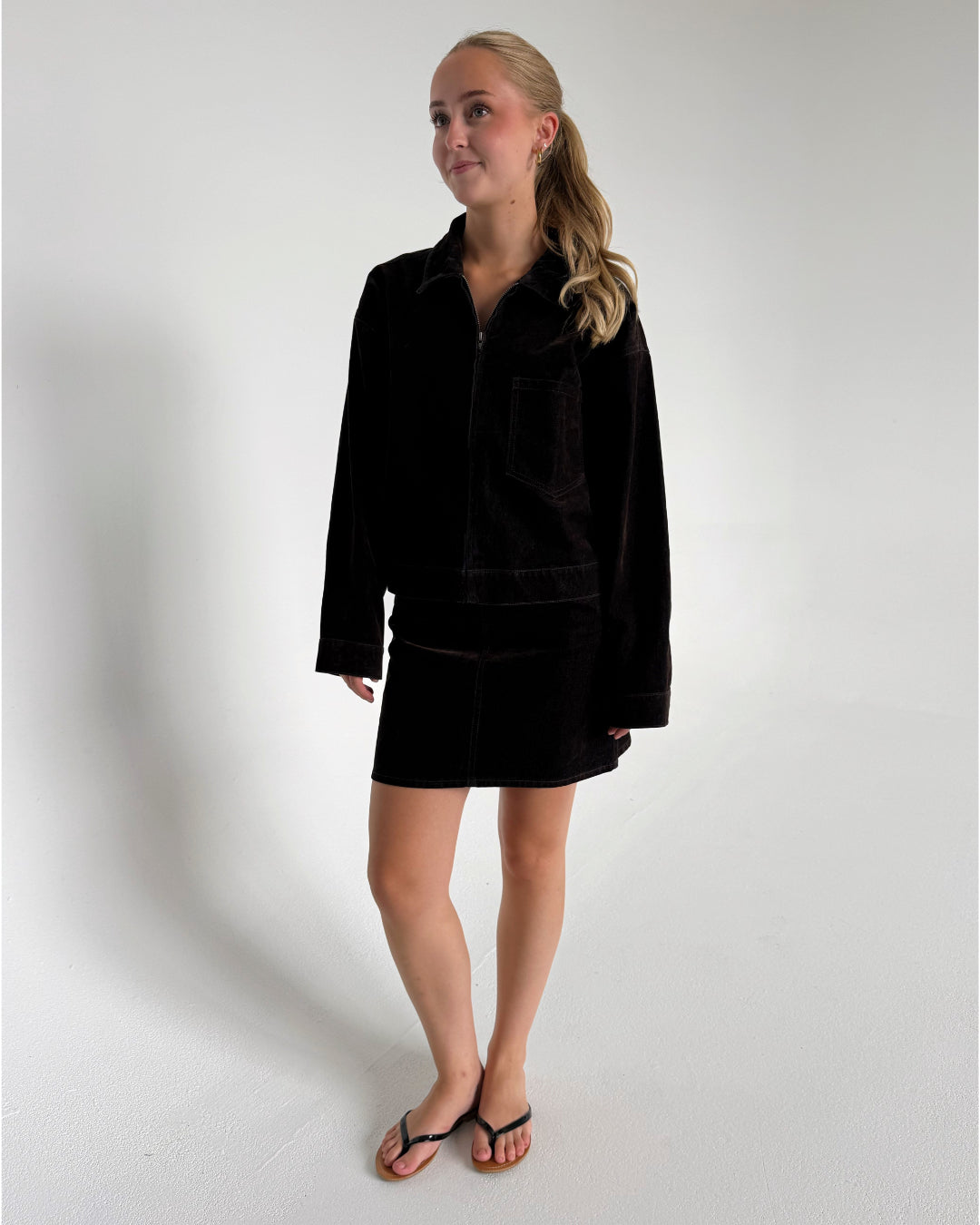 Modelfoto af pige der bærer Mia jakke i brun og Mia nederdel i brun. Alt fra BySofieSønderby