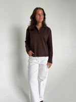 Modelfoto af pige der bærer en brun Millie bluse, samt hvide Nanna jeans. Alt fra BySofieSønderby