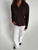 Modelfoto af pige der bærer en brun Millie bluse, samt hvide Nanna jeans. Alt fra BySofieSønderby