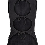 En sort, ærmeløs top med tre runde udskæringer foran, hver bundet med en snor. Stoffet har en let tekstur, formgivet til afslappet brug.