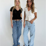 Modelfoto af to piger. Den en bærer en sort top og blå jeans, den anden pige bærer en hvid top og blå Nanna jeans. Alt fra BySofieSønderby.