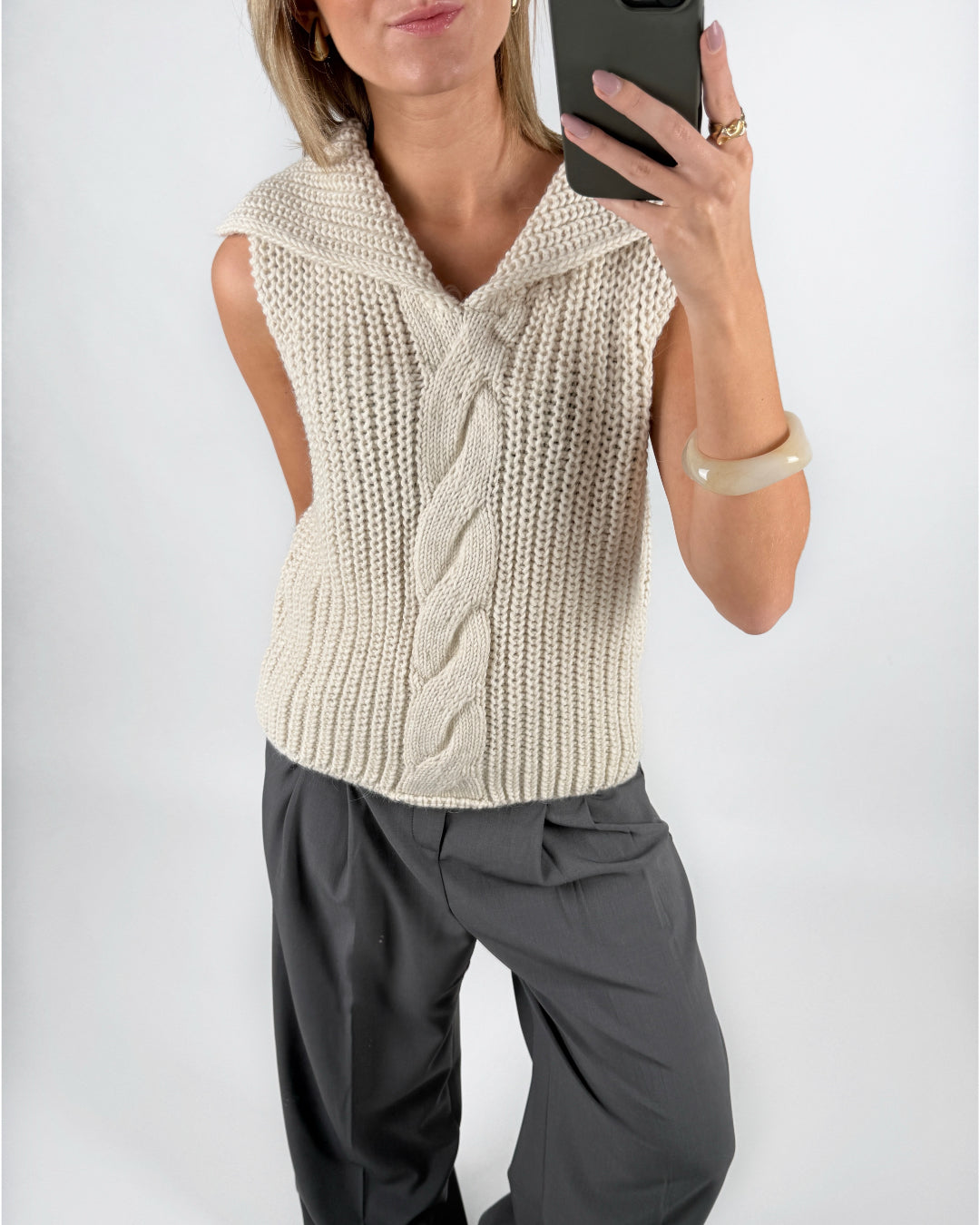 Modelfoto af pige i beige OCEAN strikvest med kabelstrik-detalje  og grå LISA bukser. Alt er fra BySofieSønderby.