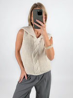 Modelfoto af pige i beige OCEAN strikvest med kabelstrik-detalje  og grå LISA bukser. Alt er fra BySofieSønderby.