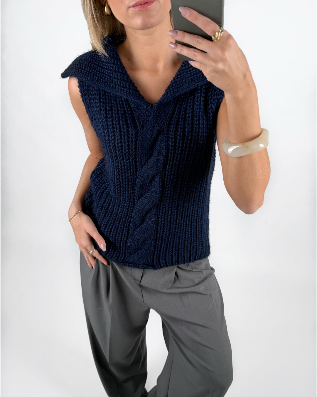 Modelfoto af pige i navy OCEAN strikvest med kabelstrik-detalje  og grå LISA bukser. Alt er fra BySofieSønderby.