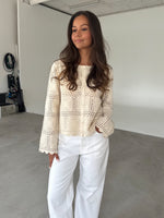 Modelfoto af pige som bærer en cremefarvet ORELLA cardigan med knapper, samt hvide jeans. Alt er fra BySofieSønderby