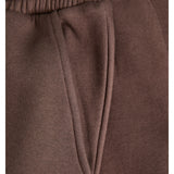 Brune joggebukser med elastisk linning og en lomme. Stoffet ser blødt og komfortabelt ud.
