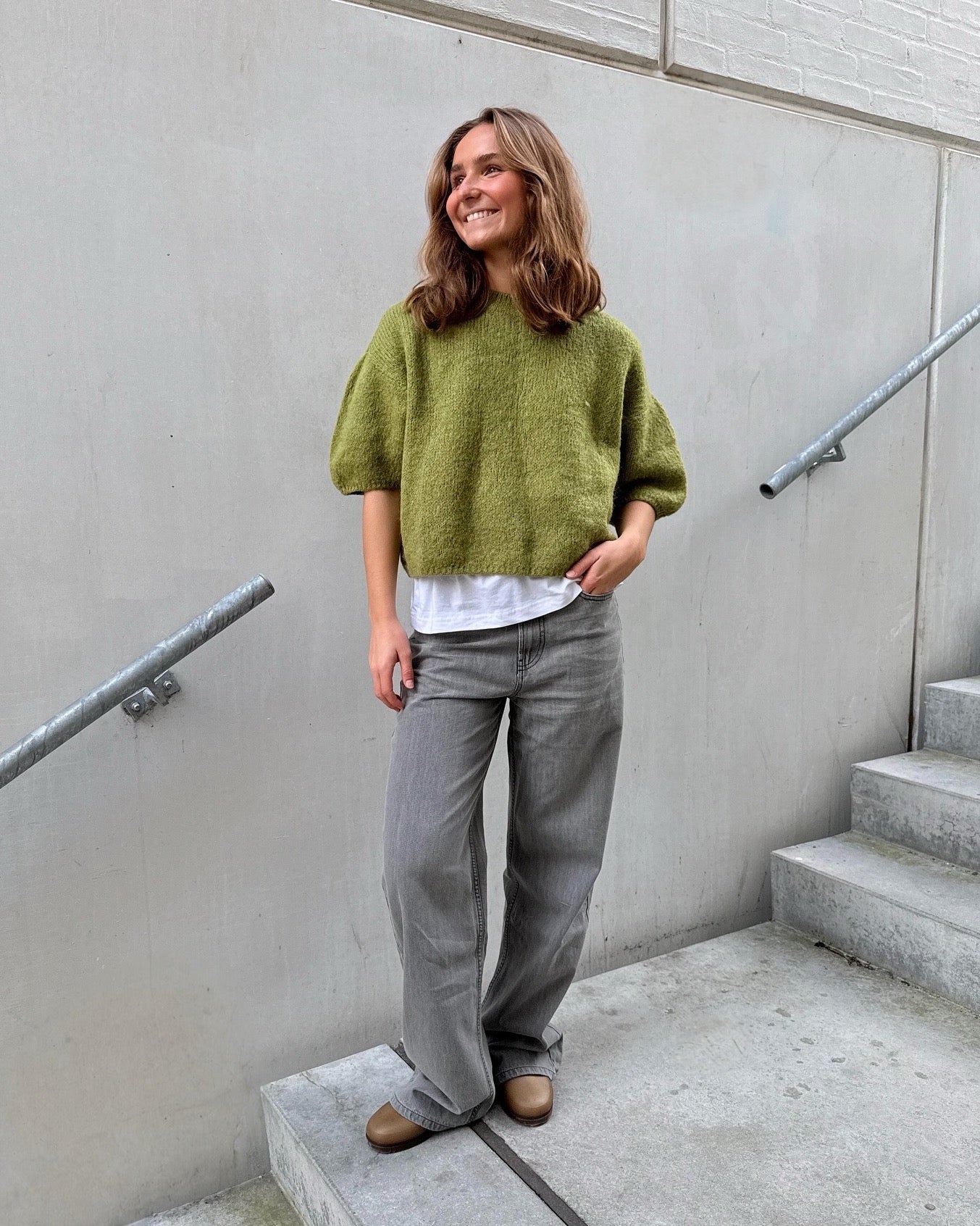 Modelfoto af pige i grøn POPPY strik, samt grå NANNA jeans. Alt er fra BySofieSønderby.
