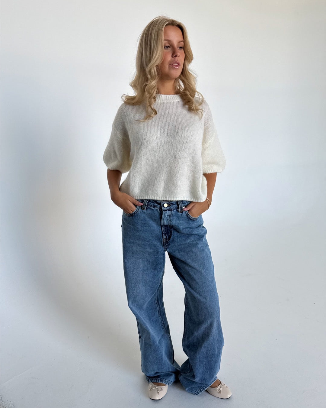 Modelfoto af pige i hvid Poppy strik t-shirt og blå Nanna jeans. Alt er fra BySofieSønderby