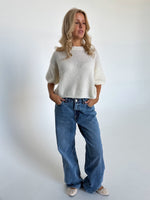 Modelfoto af pige i hvid Poppy strik t-shirt og blå Nanna jeans. Alt er fra BySofieSønderby