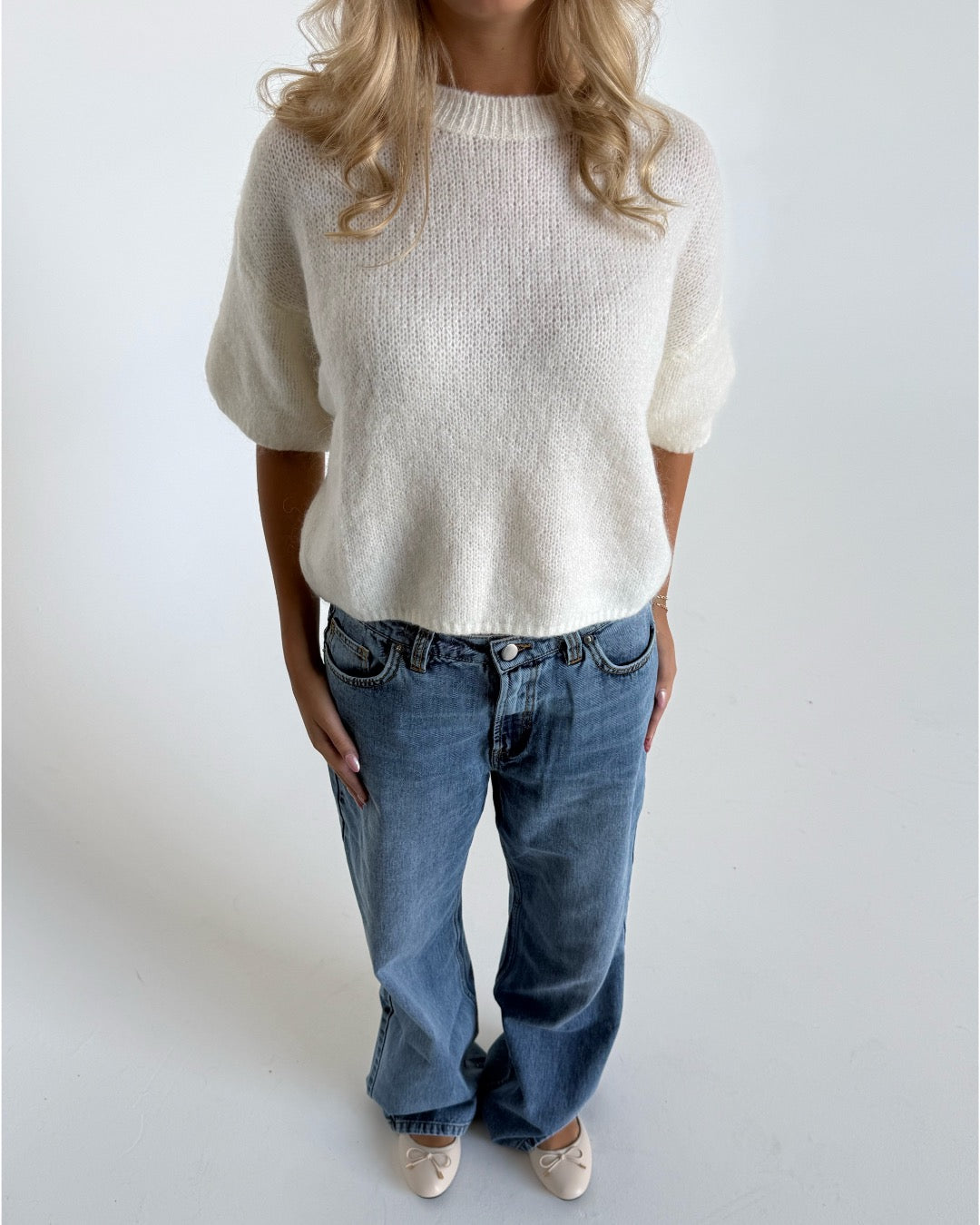Modelfoto af pige i hvid Poppy strik t-shirt og blå Nanna jeans. Alt er fra BySofieSønderby