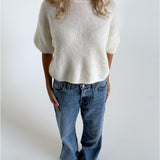 Modelfoto af pige i hvid Poppy strik t-shirt og blå Nanna jeans. Alt er fra BySofieSønderby