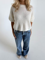 Modelfoto af pige i hvid Poppy strik t-shirt og blå Nanna jeans. Alt er fra BySofieSønderby
