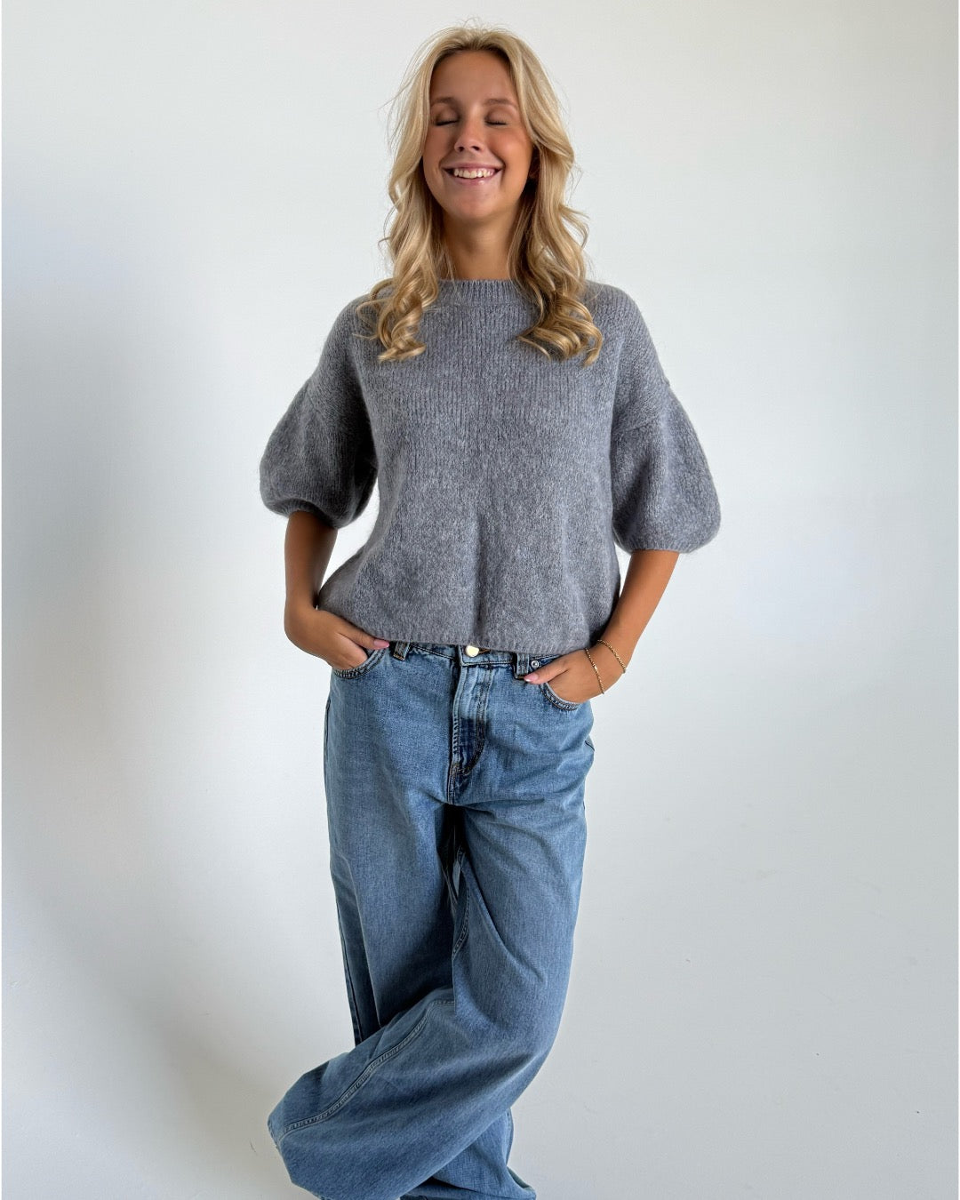Modelfoto af pige i mørkegrå Poppy strik t-shirt og hvide Nanna jeans. Alt er fra BySofieSønderby