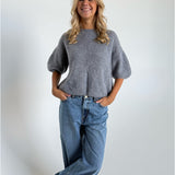 Modelfoto af pige i mørkegrå Poppy strik t-shirt og hvide Nanna jeans. Alt er fra BySofieSønderby