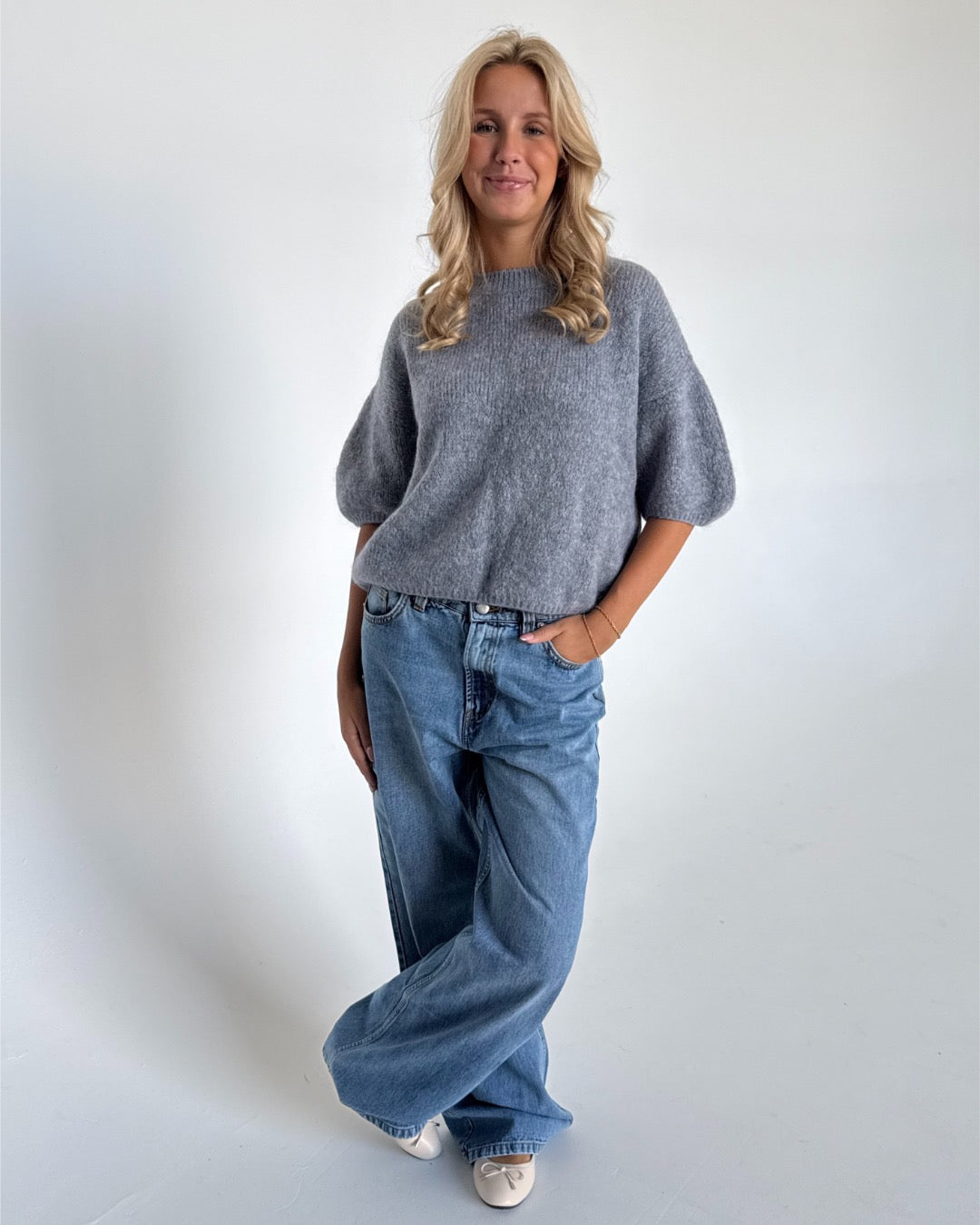Modelfoto af pige i mørkegrå Poppy strik t-shirt og hvide Nanna jeans. Alt er fra BySofieSønderby