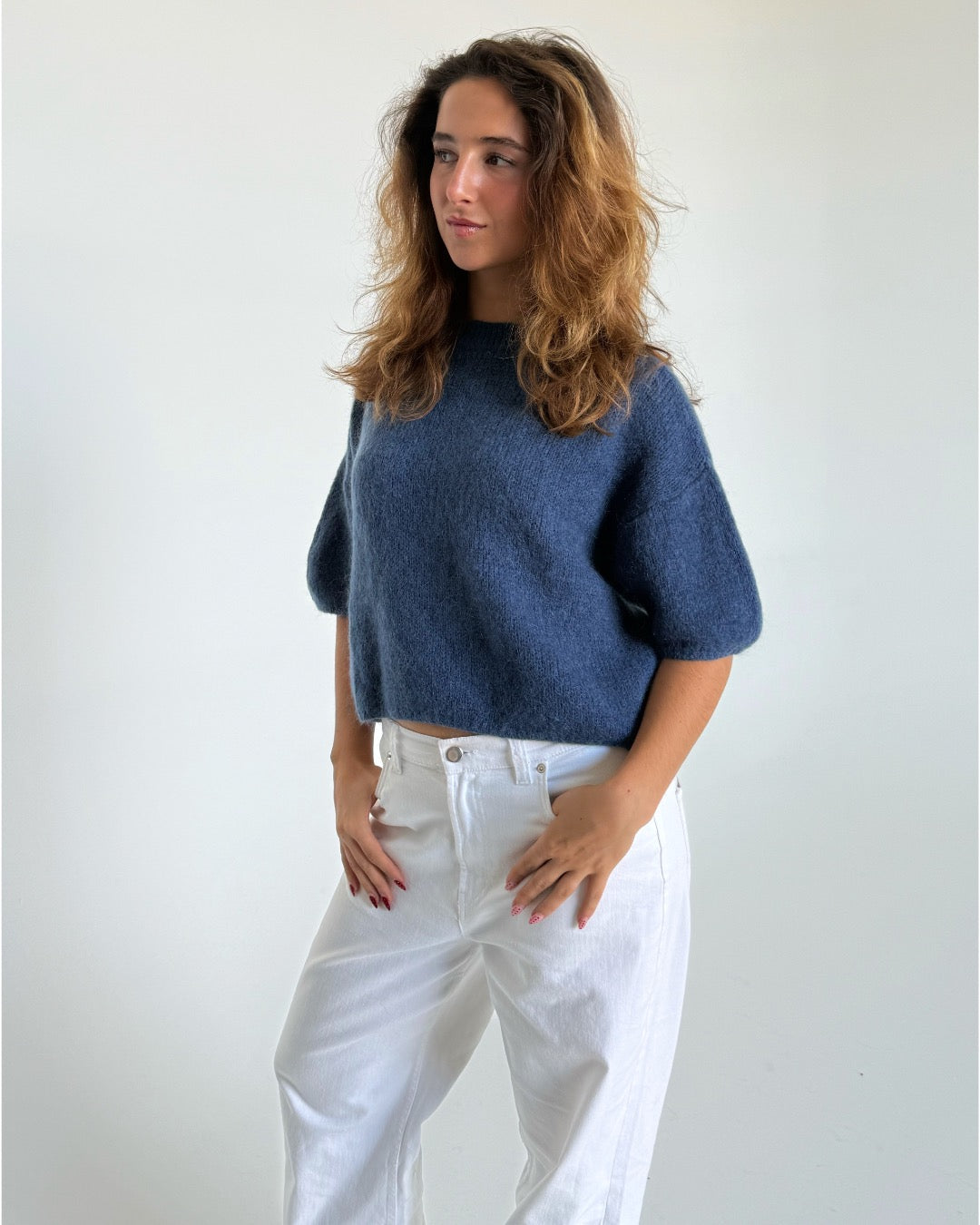 Modelfoto af pige i blå Poppy strik t-shirt og hvide Nanna jeans. Alt er fra BySofieSønderby
