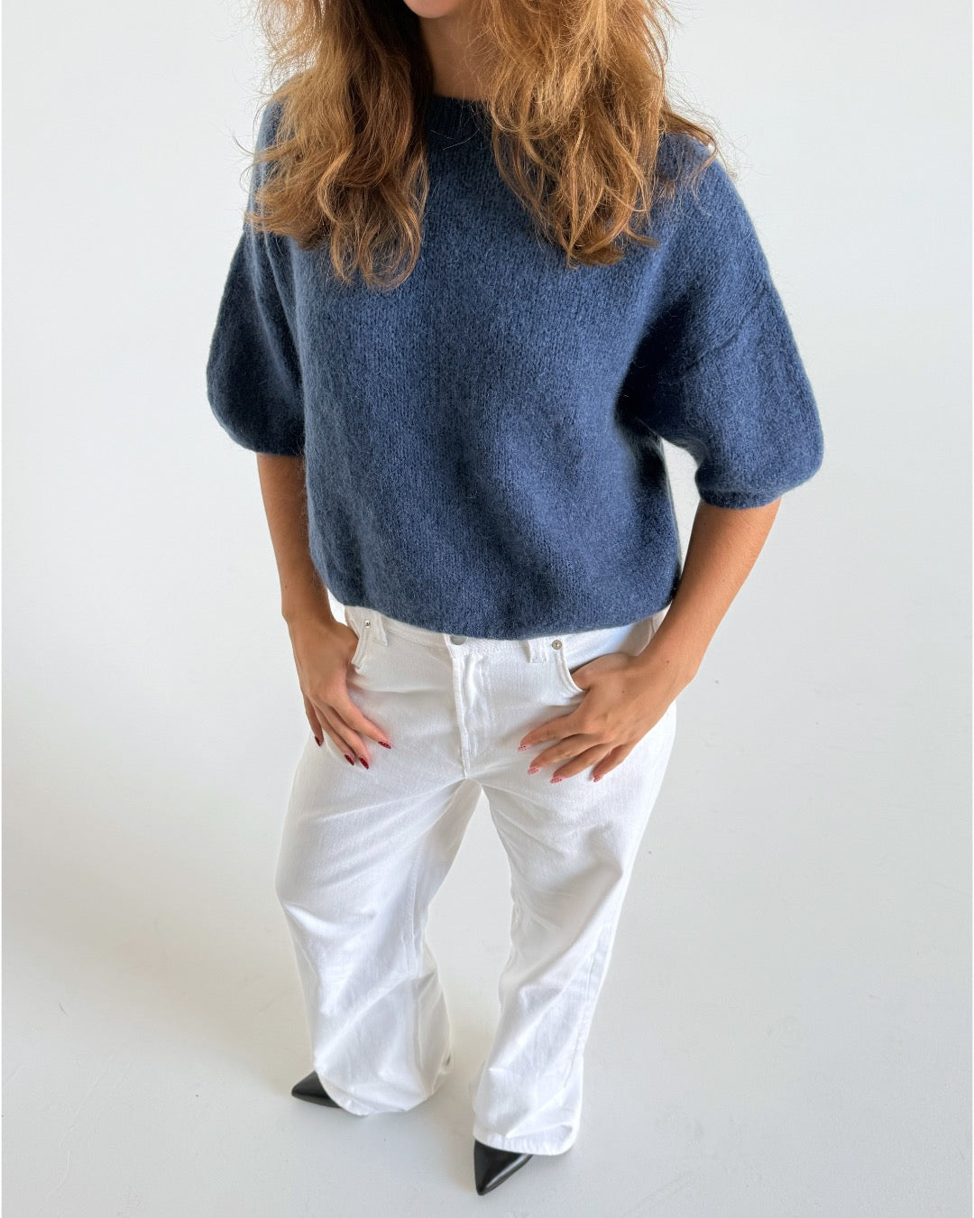Modelfoto af pige i blå Poppy strik t-shirt og hvide Nanna jeans. Alt er fra BySofieSønderby