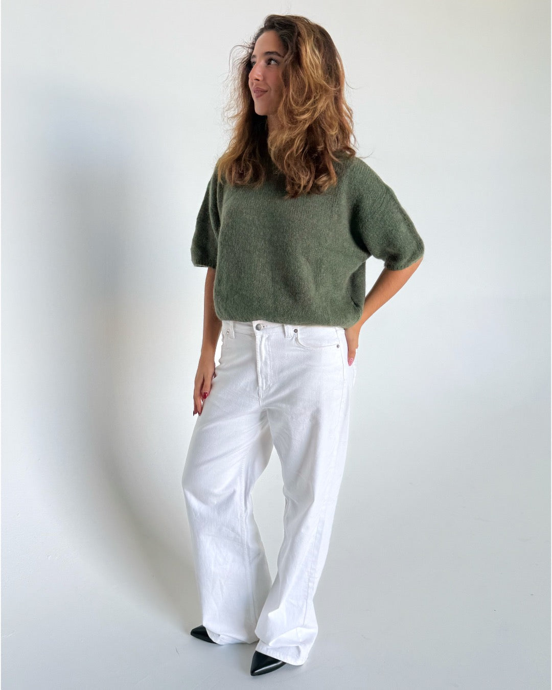 Modelfoto af pige i kaki Poppy strik t-shirt og hvide Nanna jeans. Alt er fra BySofieSønderby