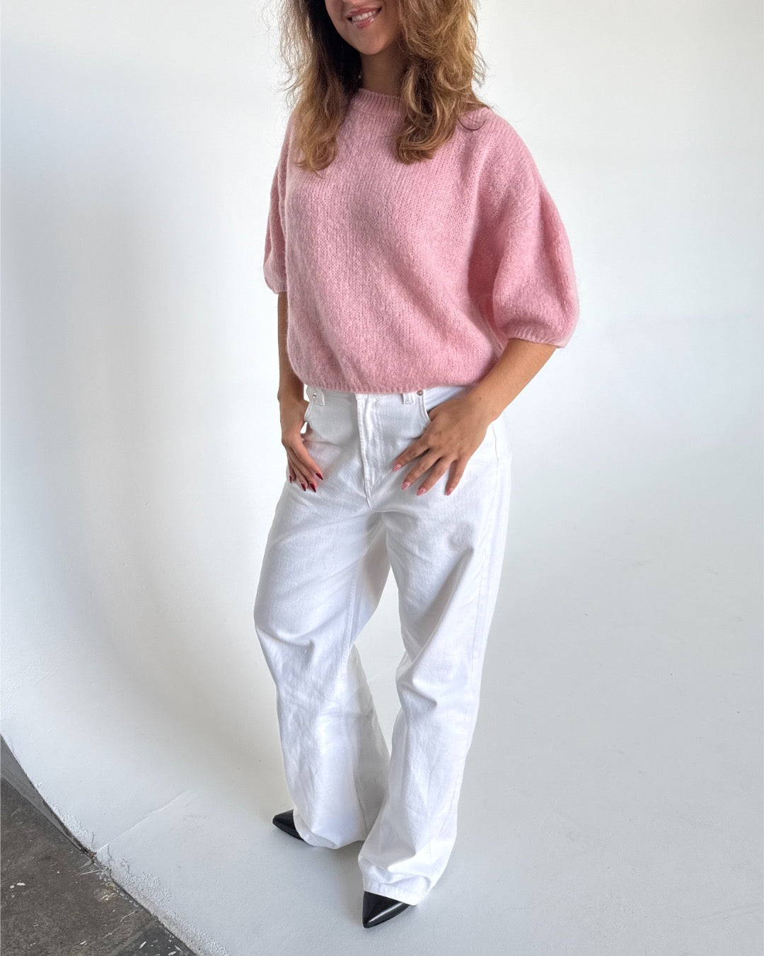 Modelfoto af pige i lyserød Poppy strik t-shirt og hvide Nanna jeans. Alt er fra BySofieSønderby