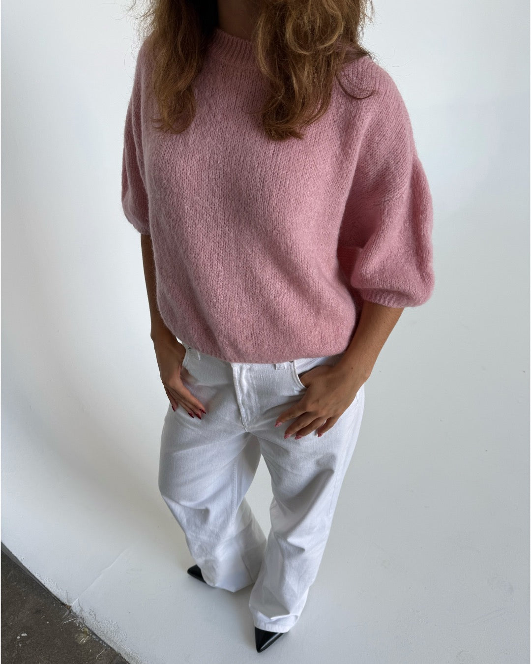 Modelfoto af pige i lyserød Poppy strik t-shirt og hvide Nanna jeans. Alt er fra BySofieSønderby