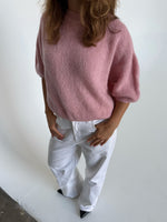 Modelfoto af pige i lyserød Poppy strik t-shirt og hvide Nanna jeans. Alt er fra BySofieSønderby