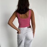 Modelfoto af pige som bærer en Posie top i pink, samt et par hvide Nanna jeans. Baggrund hvid. Alt fra By Sofie Sønderby