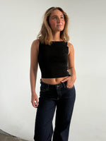 Modelfoto af pige som bærer en Posie top i sort, samt et par mørkeblå jeans. Alt fra By Sofie Sønderby