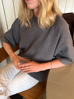Modelfoto af pige der bærer Reynard strik t-shirt i grå, samt hvide bukser. Alt fra BySofieSønderby