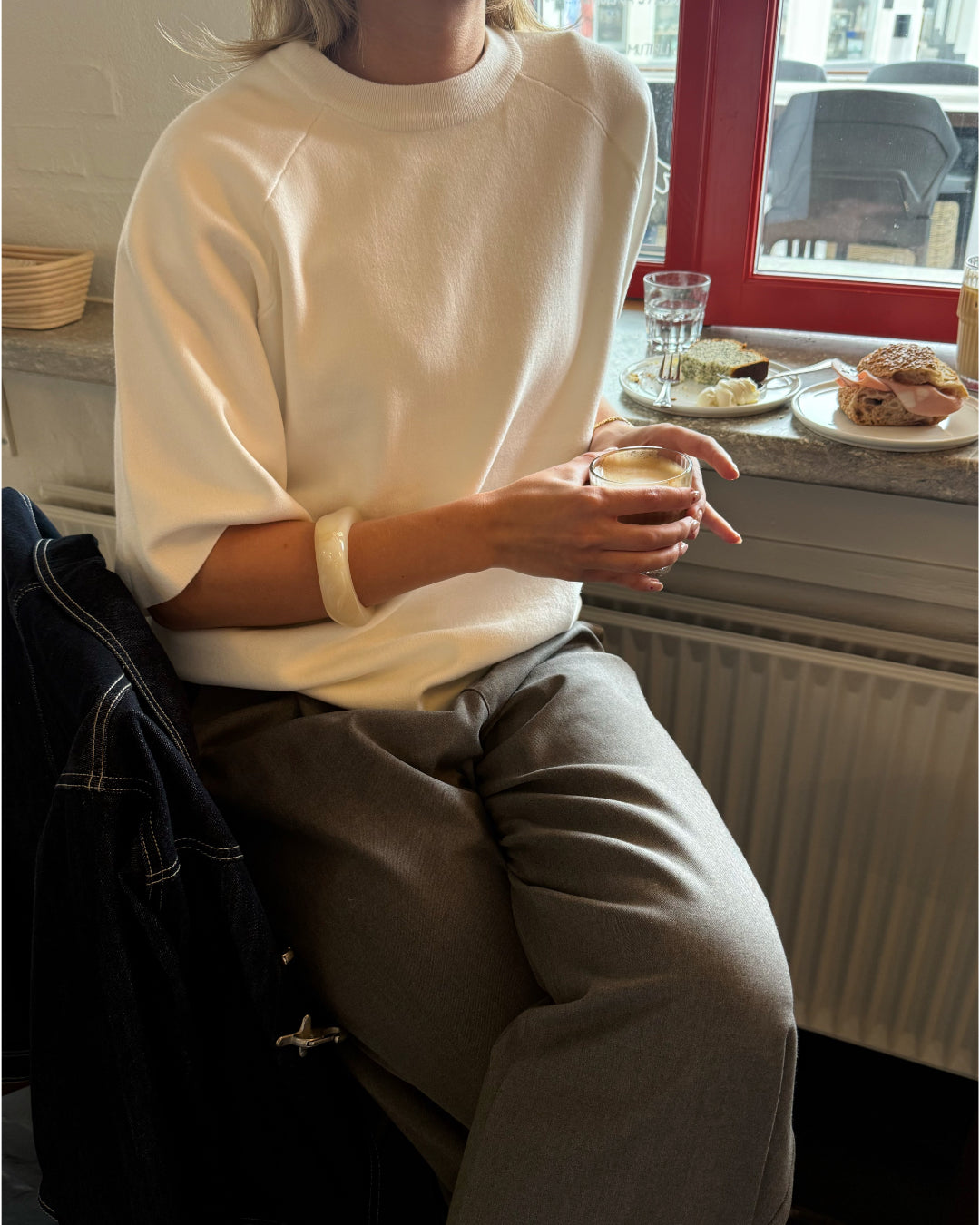 Modelfoto af pige der bærer Reynard strik t-shirt i hvid, samt grå bukser. Alt fra BySofieSønderby