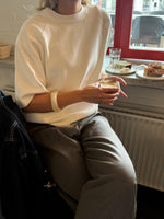 Modelfoto af pige der bærer Reynard strik t-shirt i hvid, samt grå bukser. Alt fra BySofieSønderby