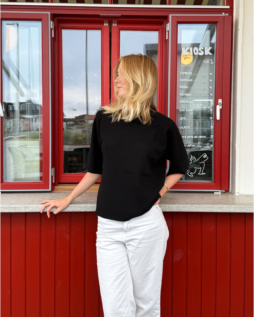 Modelfoto af pige der bærer Reynard strik t-shirt i sort, samt hvide bukser. Alt fra BySofieSønderby