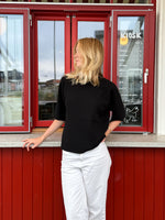 Modelfoto af pige der bærer Reynard strik t-shirt i sort, samt hvide bukser. Alt fra BySofieSønderby