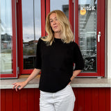 Modelfoto af pige der bærer Reynard strik t-shirt i sort, samt hvide bukser. Alt fra BySofieSønderby