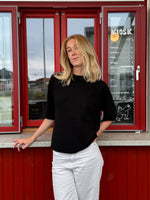 Modelfoto af pige der bærer Reynard strik t-shirt i sort, samt hvide bukser. Alt fra BySofieSønderby